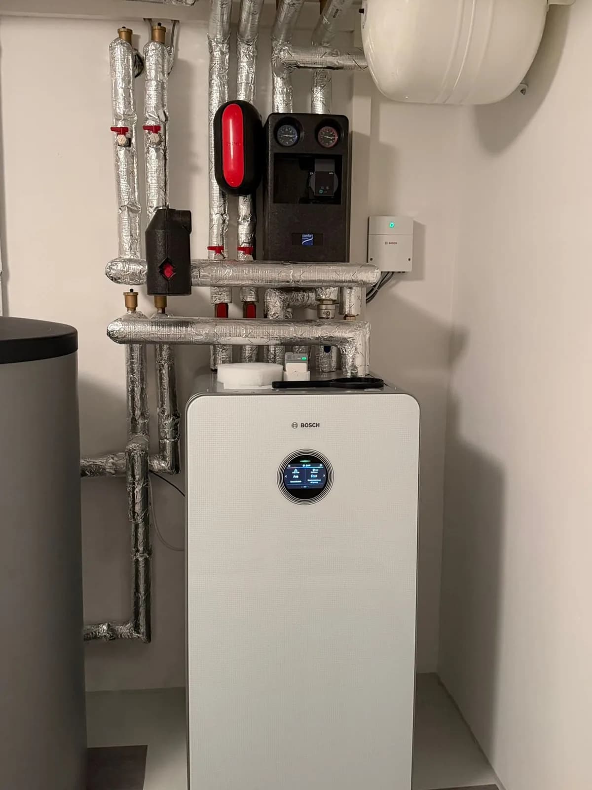 Bosch-Wärmepumpe mit Pufferspeicher und gedämmter Verrohrung im Technikraum